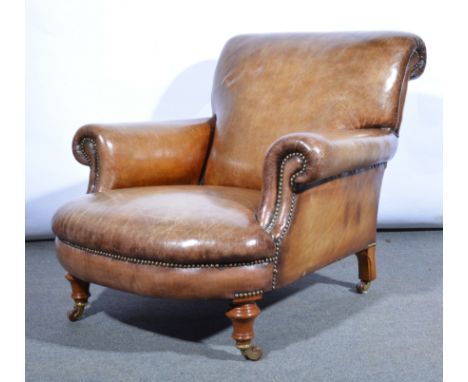 A Gentleman's  Edwardian armchair, re-upholstered in brown studded leather, turned legs to front with ceramic castors.