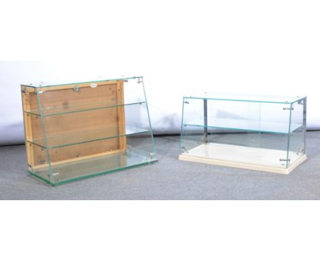 Two glass table top display cabinets, one with single shelf and plastic base with glass sliding doors, overall 60cm x 26cm x 