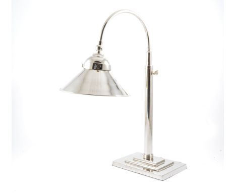 A modern nickel-plated adjustable desk lamp in the Art Deco style, the coolie design shade on curved arm supported on a stepp