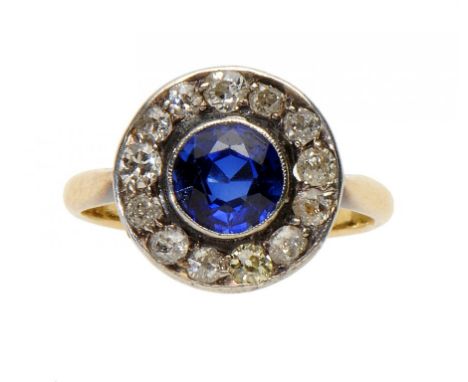 A SAPPHIRE AND DIAMOND CLUSTER RING, C1950 in gold, marked 18ct, size O ++One of the surrounding diamonds of noticeably diffe