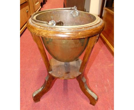 An early 20th century walnut low jardiniere stand, having removable swing handled brass planter and floral gilt metal mounts,