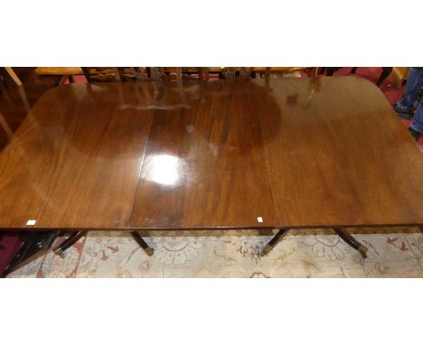 A Regency style mahogany D-end twin pillar extending dining table having two extra drop-in leaves, raised on outswept support