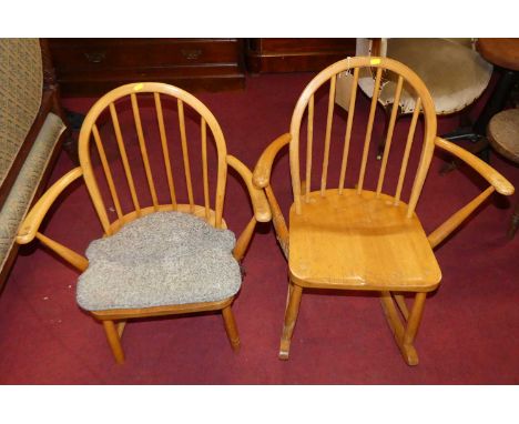 An Ercol blond elm stickback rocking elbow chair; together with a further Ercol stickback elbow chair (2)Would have been a pa