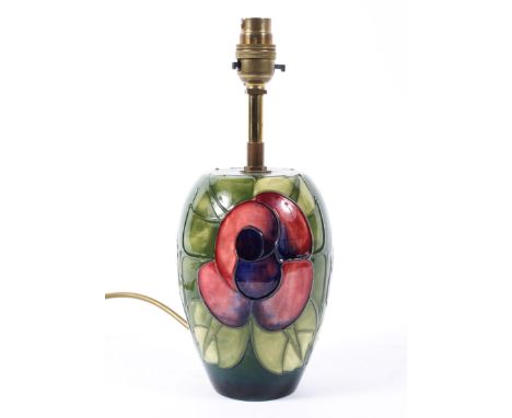 A Moorcroft table lamp decorated with a scrolled red flower on a green ground 43cm high.