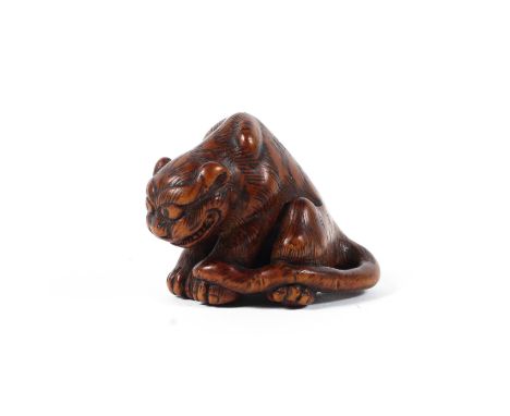 A 19th century wood netsuke of a tiger in the style of Masanao, with raised haunches and protruding eyes, the fur finely deli