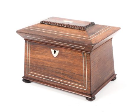 A Regency rosewood inlaid sarcophagus shaped two section tea caddy, the top inlaid with metal stringing,raised on bun feet 23