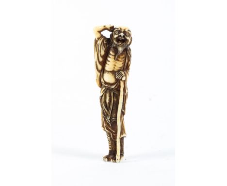 An 18th/19th century ivory netsuke of a standing sennin, his right arm raised to his head, his left resting on a staff, heigh