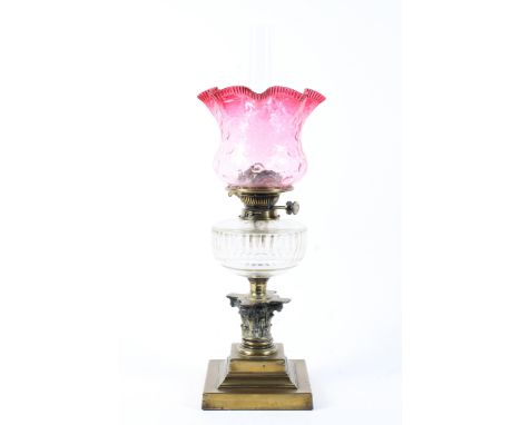 An Edwardian brass mounted oil lamp, with frilled cranberry glass shade, with Hicks Duplex No. 2 burner, on corinthian column