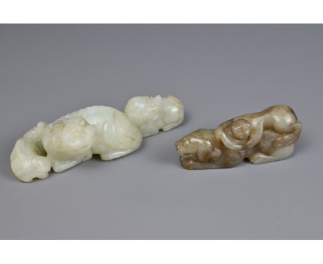 TWO CHINESE JADE CARVINGS. A pale celadon jade carving of a lion group together with a mottled celadon and brown jade figure 