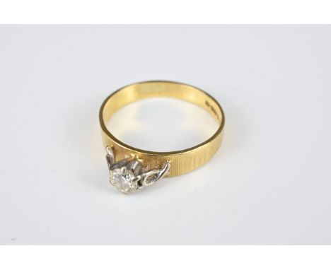 AN 18KT YELLOW GOLD AND DIAMOND SET RING. The brilliant cut diamond raised in a claw setting, on a thick 18kt gold band, hall