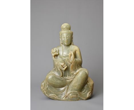 A CHINESE CELADON JADE FIGURE OF GUANYIN. The figure seated on a rock form base holding a ruyi sceptre and clasping a pearl i