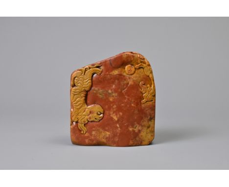 A CHINESE CARVED SOAPSTONE SEAL, QING DYNASTY. Orange and red tones of boulder form carved in relief with dragon under a moon