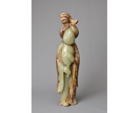 A CHINESE CELADON JADE FIGURE OF A LADY HOLDING A FAN. Dressed in a long robe with hair tied up clasping a fan. 30.5cm tallGo