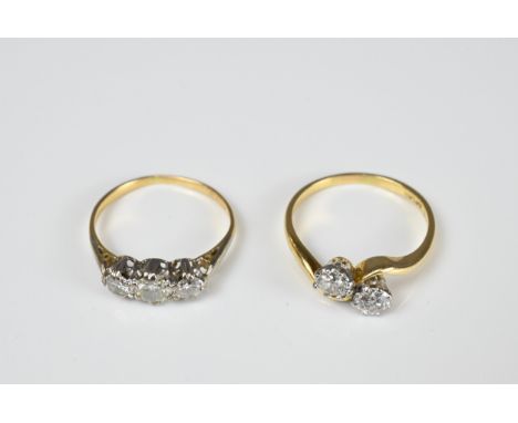 AN 18KT YELLOW GOLD AND PLATINUM TWO-STONE DIAMOND RING AND A YELLOW METAL AND THREE STONE DIAMOND RING. The first with brill