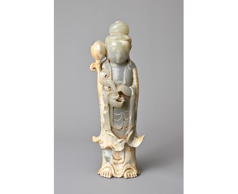 A CHINESE JADE FIGURE OF GUANYIN. The figure standing dressed in flowing robes with hair in a topknot holding a lotus spray. 