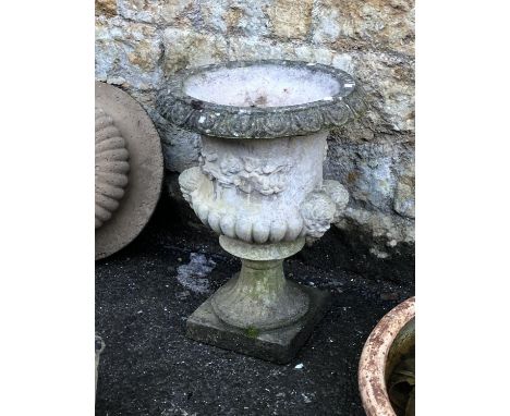 A composite stone urn planter with twin mask lugs 