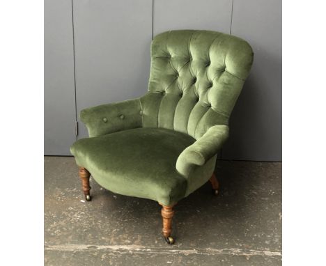 A Victorian low button back armchair, in green upholstery, on turned legs and casters, 77cmW 