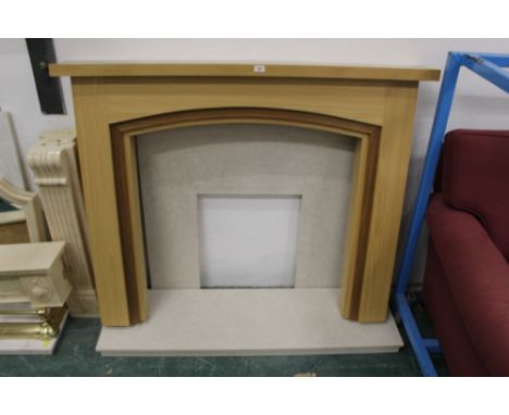 A modern light oak fire surround with marble hearth and back
