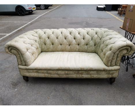 A late 19th/early 20th century Chesterfield sofa with floral Damask button back upholstery, raised on turned feet and castors