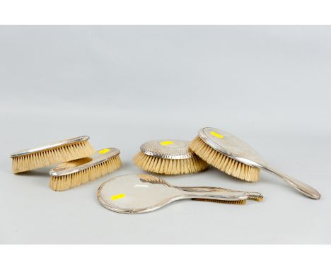 A five piece silver dressing table set of hand mirror, oval hand brush, two narrow brushes and a comb (silver of latter intac