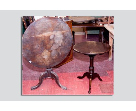 An antique mahogany tilt top tripod table having a circular top on two bearers with block mount below pegged into a turned co