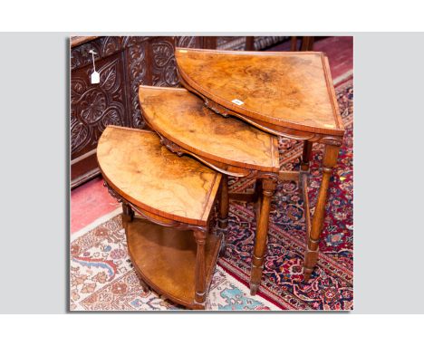 An attractive nest of three bow fronted walnut corner coffee tables, each having a curved shell apron and the smallest having