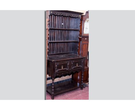 A dark oak Jacobean style dresser, shaped pierced frieze over a panel backed and shaped fronted two shelf top above a two dra