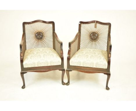 A pair of early 20th Century walnut Bergere arm chairsEach with a rattan back centered with a ring turned bull's eye over a f