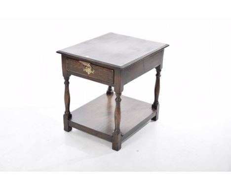 A reproduction oak lamp table The rectangular moulded top above a single frieze drawer with brass swan neck handles raised on