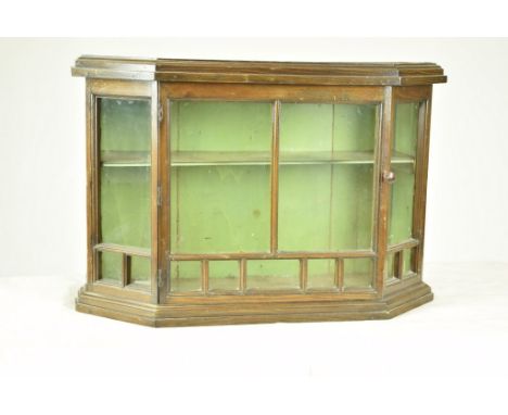 An early 20th Century walnut hanging display cabinetWith an angled bowfront and a single glazed door enclosing a single shelf