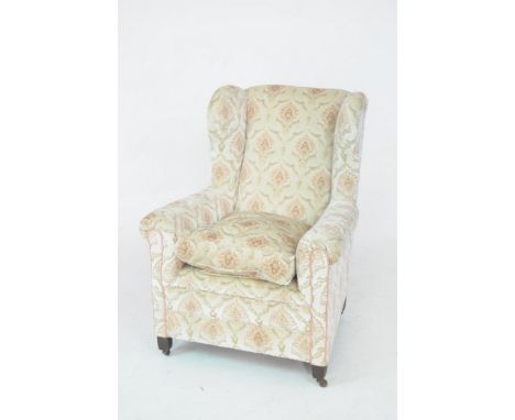 An early 20th Century wing back fireside chairWith padded arms above a single loose cushion over a padded channelled front ra