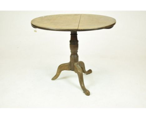 A George III mahogany tilt-top tripod tableThe circular top raised on a ring turned baluster shaft and three down swept suppo