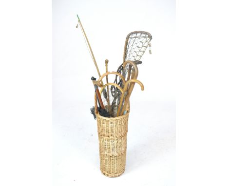 A wicker stick stand containing various canes and sticksThe tapered wicker stand, with lacrosse net, various sticks, canes an