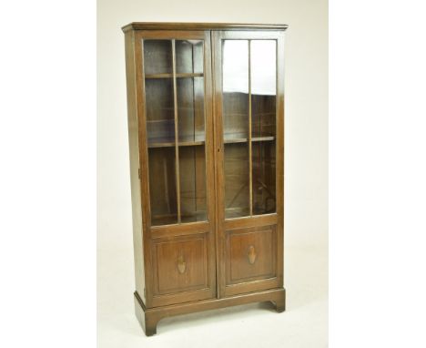 A George V oak bookcaseThe rectangular moulded top above two glazed and paneled doors enclosing three shelves raised on brack