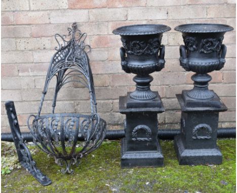 PAIR CAST IRON GARDEN URNS ON PLINTHS, decorated with scrolling foliage on laurel wreath ornamented plinth bases, urns 38cms 