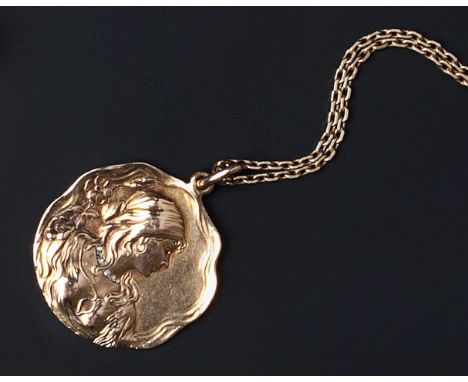 AN ART NOUVEAU MEDALLIST PENDANT, the shaped circular panel depicting a maiden in portrait profile, framed by flowerheads and