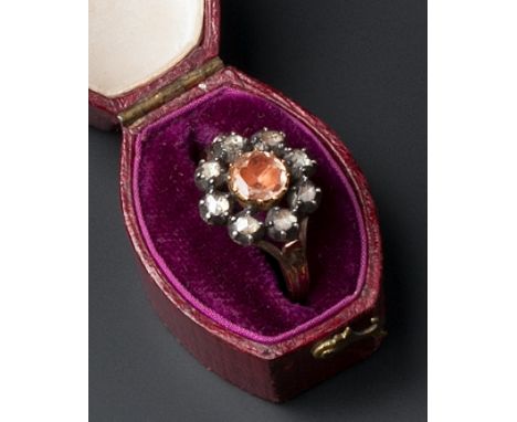 A TOPAZ AND DIAMOND CLUSTER RING, the circular-cut topaz in closed foil-backed setting, surrounded by similarly set lasque-cu