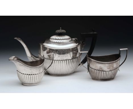 A SILVER THREE PIECE TEA SET, oval teapot with fluted lower body, matching hinged lid amd ebonised handle, 15cm high with mat