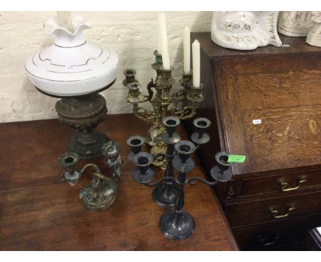 Two pairs of candlesticks with a smaller candlestick and a cast iron oil lamp with shade.
