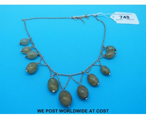 A yellow metal necklace decorated with oval jade beads