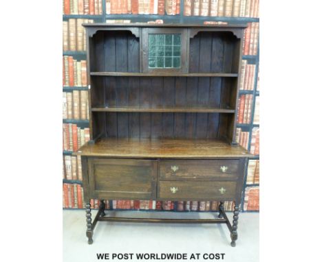 An oak dresser with plate rack above, the base fitted two drawers and a cupboard, raised on bobbin turned legs (W138 x D50 x 