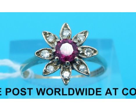 A 9ct gold ring set with a central ruby surrounded by diamonds in a floral cluster (Size Q)