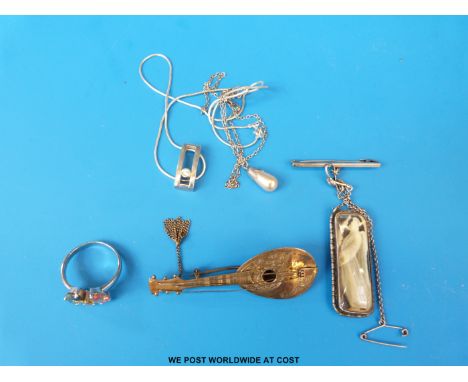 Two silver necklaces, a silver ring set with citrine, a silver brooch depicting a religious figure and a small lute 