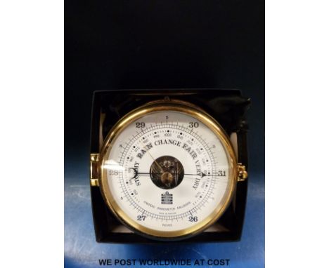 A brass dial-shaped aneroid barometer in marine style with white dial