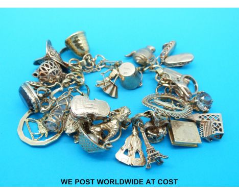 An 18ct gold charm bracelet with 25 9ct and 18ct gold charms including fob, dog, shoe, helmet etc (90.4g)