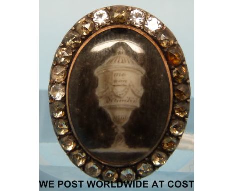 A Georgian yellow metal brooch set with an ivory panel depicting an urn with inscription in a border with paste decoration, e