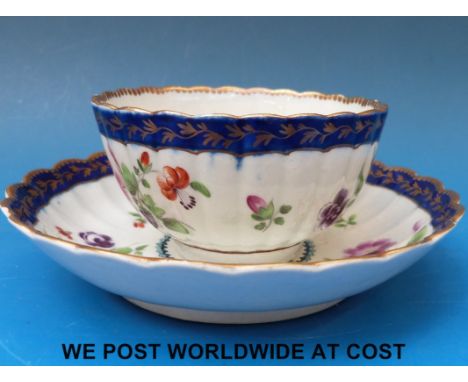 A Worcester Dr Wall period blue border fluted cup and saucer, circa 1770-75 crescent mark, painted with colourful floral spra