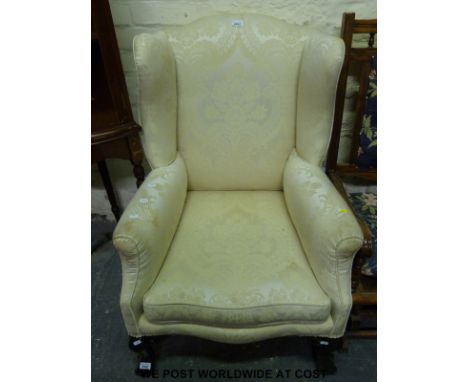 An upholstered wing back armchair raised on carved ball & claw feet