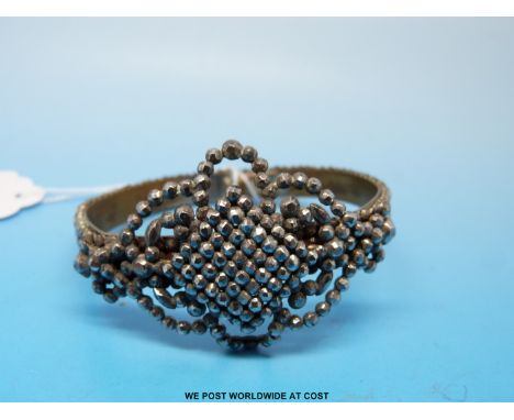 A Victorian cut steel bangle formed of four rows of single faceted stones set with a diamond shaped section surrounded by fol