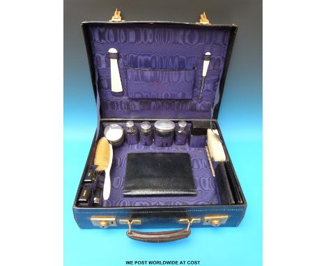 A leather gentleman's travelling vanity set comprising ivory backed brushes, shoe horn and button hook, hallmarked silver mou
